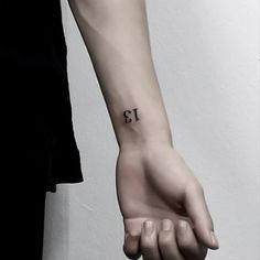 a person's wrist with a small tattoo on it that reads 13, and the number thirteen