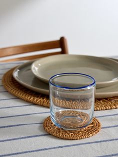 there is a glass on the placemat next to a plate with a fish in it