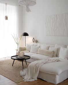 a living room with white furniture and wood flooring, including a large sectional couch