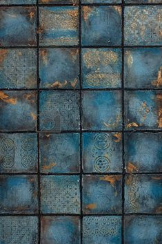 an old blue tile wall with rusted metal squares and designs on the tiles in it