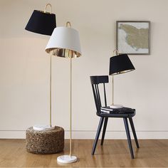 two lamps and a chair in a room with wood flooring, one lamp has a black shade on it