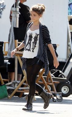 a woman walking down the street wearing black and white clothing with her hair in a bun