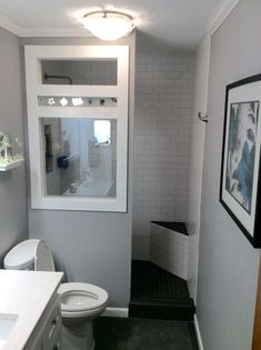 a white toilet sitting in a bathroom next to a sink and shower stall under a window