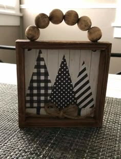 a wooden frame with black and white christmas trees on it, sitting on top of a table