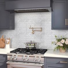 a stove top oven sitting inside of a kitchen next to gray cabinets and white counter tops