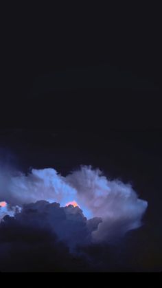 an airplane is flying in the sky at night with some clouds behind it and one plane on the ground