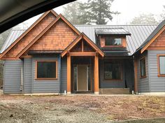 a gray house with wood trim and metal roof