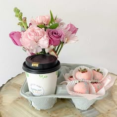 pink flowers in a vase next to a cup of coffee and some strawberries on a tray