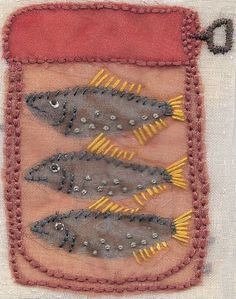 three fish in a red and yellow frame on a piece of fabric with stitching