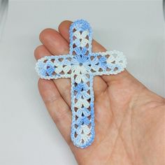 a hand holding a crocheted blue and white cross