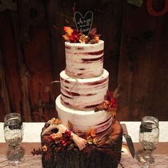 a three tiered cake sitting on top of a table next to two wine glasses