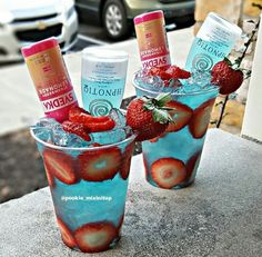 two glasses with strawberries on them sitting on a table