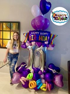 a woman standing in front of a birthday balloon display