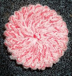 a crocheted pink and white object on the ground in front of a black surface