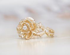 a close up of a gold ring on a white surface with a diamond in the middle