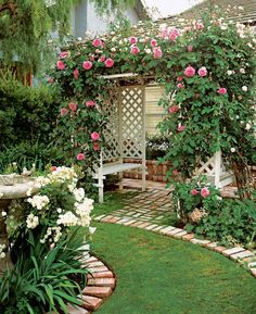 a white bench sitting in the middle of a garden next to pink flowers and greenery