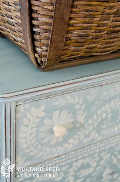 a basket sitting on top of a dresser next to a blue drawer with white drawers