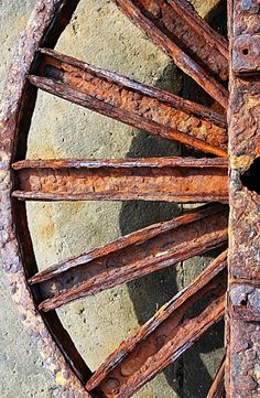 an old rusty wagon wheel with rusted spokes on the side of a building