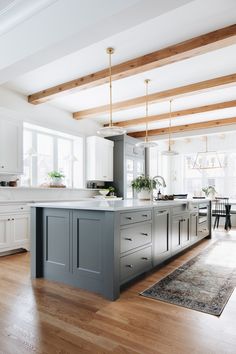 an instagramted photo of a kitchen with white cabinets and gray island