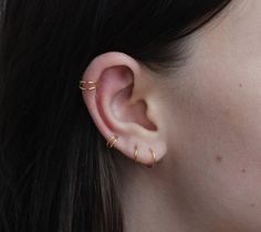 a close up of a person's ear with two small gold rings on it