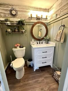 a white toilet sitting next to a sink in a bathroom under a mirror and lights