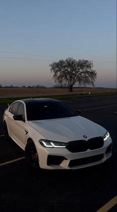 a white car parked in a parking lot next to an empty road with trees on the other side