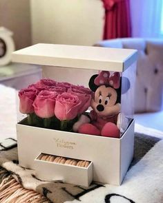 a minnie mouse stuffed animal in a box with roses