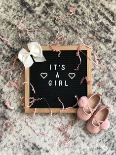 it's a girl sign with pink baby shoes on the floor next to it