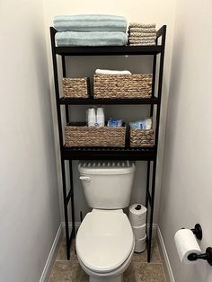 a bathroom with a toilet and shelving unit filled with towels, soaps, and other items