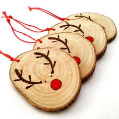 three wooden ornaments with reindeer faces on them, hanging from red string in front of an instagram page