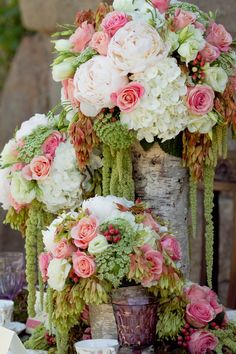 a bouquet of white and pink flowers sitting on top of a wooden table next to rocks