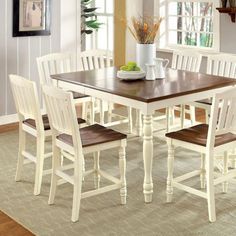 a dining room table with chairs and a vase on top of it in front of a window