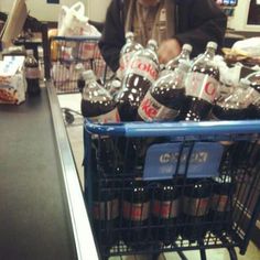 a man sitting in a grocery cart filled with bottled water and soft drinks at a store