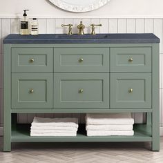 a bathroom vanity with two towels stacked on the counter and a round mirror above it