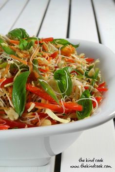 a white bowl filled with vegetables and sprouts on top of a wooden table