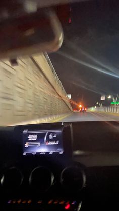 the dashboard of a car driving on a highway at night with lights in the background