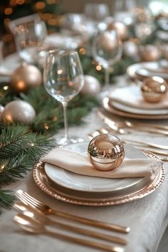 the table is set with white and gold plates, silverware, and christmas decorations