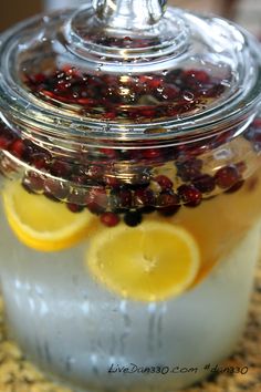 a jar filled with lemons and cranberries sitting on top of a counter