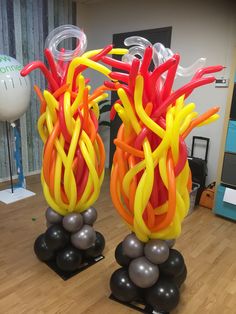 two vases made out of balloons sitting on top of a wooden floor next to each other