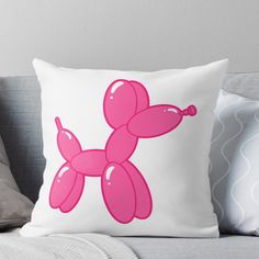 a pink balloon dog sitting on top of a couch next to pillows and pillow covers