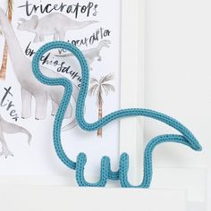 there is a blue string sculpture on the wall next to a white framed print with dinosaurs