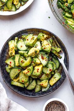 two plates filled with cucumbers and other food