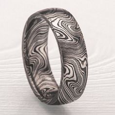 a wedding ring made out of wood on a white surface with an intricate design in the center