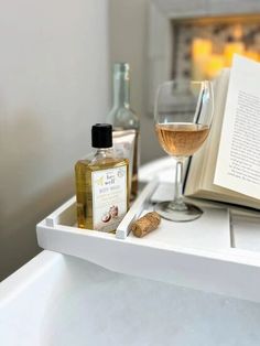 an open book and some wine glasses on a white counter with a bottle of wine