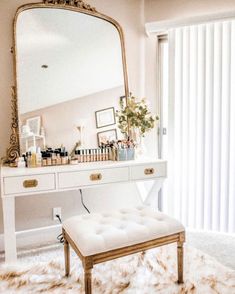 a dressing table with a mirror and stool in front of it, next to a window