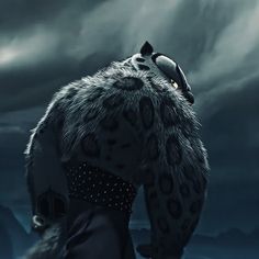 an animal with its back turned to the camera, standing in front of dark clouds