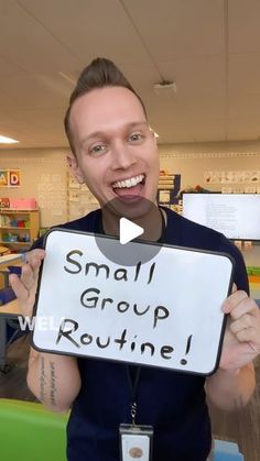 a man holding up a sign with the words small group routine in front of him