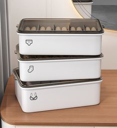 three white containers are stacked on top of each other, with eggs in the bottom