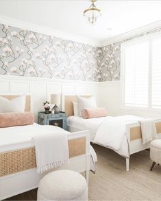 two beds in a bedroom with floral wallpaper on the walls and white bedding