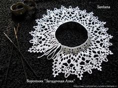 a white lace doily sitting on top of a black surface next to two knitting needles